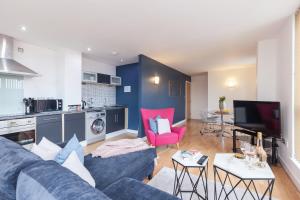a living room with a blue couch and a kitchen at KSpace @ West One in Sheffield