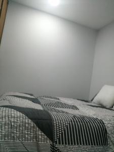 łóżko w pokoju z białą ścianą w obiekcie hostal mancora monjitas 755 w mieście Santiago