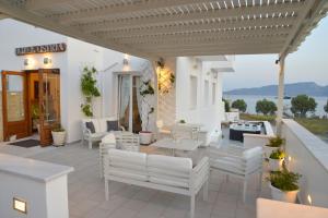 un patio con mobili bianchi e vista sull'acqua di Ostria Hotel  ad Adámas