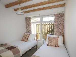 2 camas en una habitación con ventana en The Doll's House en Harlech