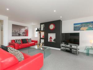 a living room with red couches and a tv at Chapel View in St Ives