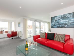 a living room with a red couch and a glass table at Chapel View in St Ives