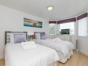 two white beds in a room with a tv at Chapel View in St Ives