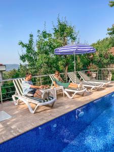 um homem e uma mulher sentados em cadeiras de jardim ao lado de uma piscina em Havuzlu Mustakil Lüx Villa Doğa SAPANCA 150 MT2 em Sapanca