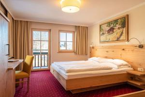 a bedroom with a bed and a desk and a window at Hotel Senningerbräu in Bramberg am Wildkogel +137 photos