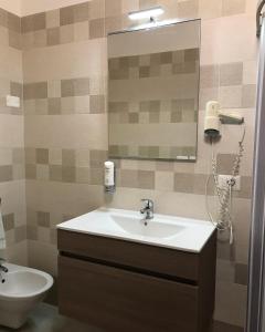 La salle de bains est pourvue d'un lavabo, d'un miroir et de toilettes. dans l'établissement Albergo Europa, à Marina di Mancaversa