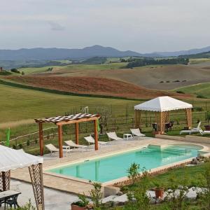 basen z białymi leżakami i parasolami w obiekcie Agriturismo La Spiga w mieście Montecatini Val di Cecina
