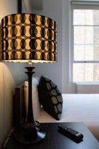 uma lâmpada sentada numa mesa com um comando à distância em Concept Serviced Apartments by Concept Apartments em Londres