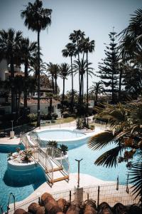 a large swimming pool with palm trees in a resort at Anais Marbella in Marbella