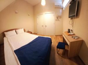 a bedroom with a bed and a desk and a television at Marotel in Tbilisi City