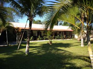 dom z palmami przed nim w obiekcie Pousada do Veleiro Azul w mieście Angra dos Reis