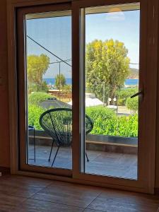 a sliding glass door with a chair on a balcony at Seaview-Apartments in Palaia Fokaia