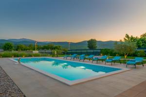 a swimming pool with blue chairs and a table at Villa Lukrecia, Luxury Villa in Imotski-Makarska in Donji Proložac