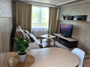 een woonkamer met een tafel en een televisie bij Zvejnieku Alejas Apartment in Liepāja