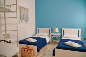 2 camas en una habitación azul y blanca con espejo en Casa Levante, en Monopoli