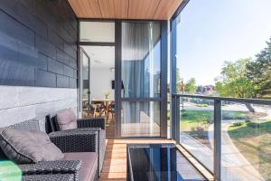 a patio with two chairs and a table on a balcony at Sunset Apartment at Sventosios Vartai in Palanga