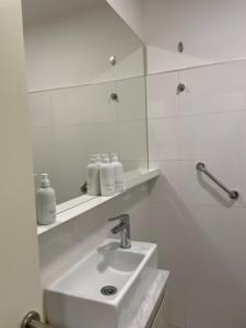 ein weißes Badezimmer mit Waschbecken und Spiegel in der Unterkunft Departamentos boutique in La Falda + 35 Fotos