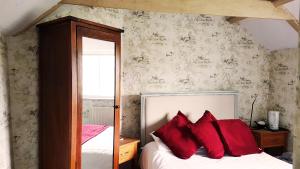 1 dormitorio con 1 cama con almohadas rojas en The Royal Oak Duddington en Stamford