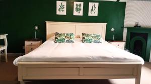 a bedroom with a white bed with a green wall at The Royal Oak Duddington in Stamford