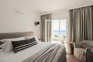 a bedroom with a bed and a chair and a window at Saint George Hotel in Chrissi Akti