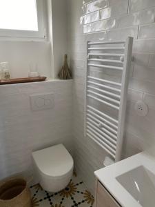 La salle de bains blanche est pourvue de toilettes et d'un lavabo. dans l'établissement Casa Nomad - appartement cozy les pieds dans l'eau, à Ploemeur