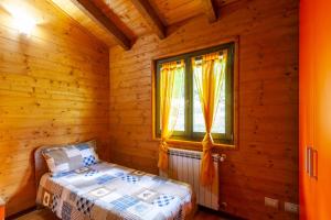 sypialnia z łóżkiem w drewnianym domku w obiekcie Villaggio Anemone Chalet Scoiattolo w mieście Capanne di Sillano