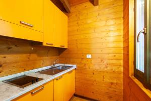 una cocina con armarios amarillos y fregadero en Villaggio Anemone - Chalet Mirtillo, en Capanne di Sillano