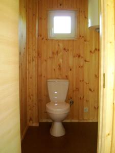 a bathroom with a toilet with a window and wooden walls at SaulesKempings in Mērsrags
