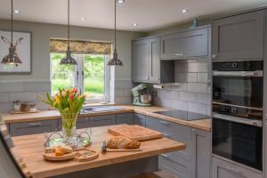 a kitchen with gray cabinets and a wooden counter top at Orchard Cottage in Alderton