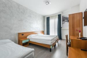 een slaapkamer met 2 bedden en een bureau bij Hotel De Nac in Nago-Torbole