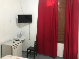 a room with a red curtain and a table and a desk at Pousada flor de Atibaia in Atibaia