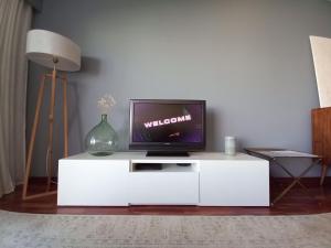 a tv on a white cabinet in a living room at Cabedelo Beach Apartment in Viana do Castelo