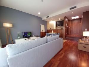 uma sala de estar com um sofá branco e uma televisão em Cabedelo Beach Apartment em Viana do Castelo