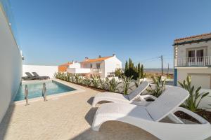 a group of white chairs sitting next to a swimming pool at Casa do Sol - By SCH in Salir de Porto