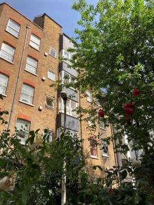 um edifício de tijolos em frente a uma árvore em Lovely 1 bedroom apartment in Waterloo em Londres