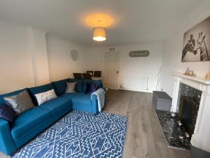 ein Wohnzimmer mit einem blauen Sofa und einem Kamin in der Unterkunft Marie’s 3 bedrooms Shakespeare house in Bedford
