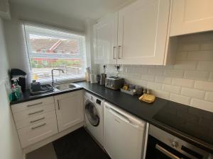 a kitchen with a sink and a washing machine at Marie’s 3 bedrooms Shakespeare house in Bedford
