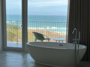 a bath tub in a bathroom with a view of the ocean at Porto Covo Praia Hotel & SPA in Porto Covo