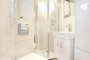 baño blanco con ducha y lavamanos en Queensborough Terrace Serviced Apartments by Concept Apartments en Londres