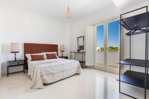 una camera bianca con un letto e una grande finestra di Villa Donna Sofia by Perle di Puglia ad Alezio Altre 55 foto
