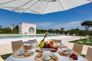 un tavolo con cibo e frutta in cima a esso, accanto a una piscina di Villa Donna Sofia by Perle di Puglia ad Alezio