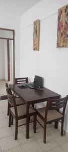 una mesa de madera con sillas y un ordenador portátil. en Lyneks Cosy Apartment en Mombasa