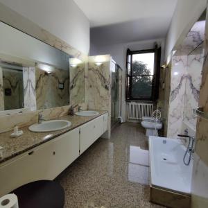 łazienka z 2 umywalkami, wanną i toaletą w obiekcie Villa Ghia w mieście Parma