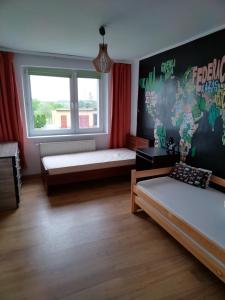een kamer met 2 bedden en een kaart aan de muur bij Wygodny apartament blisko morza in Łokciowe
