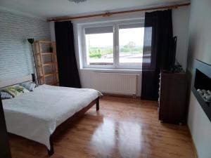una camera con un letto e una grande finestra di Wygodny apartament blisko morza a Łokciowe