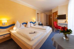 a hotel room with a large bed and a red chair at Hotel Meschenmoser in Langenargen