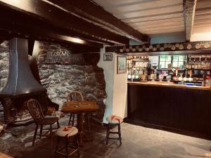 a bar with a fireplace and a table and chairs at The Crown Inn in Lanlivery