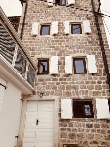 un edificio de ladrillo con puertas y ventanas blancas en Guesthouse Giraffe, en Tivat