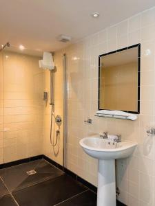 a bathroom with a sink and a shower with a mirror at The Crown Inn in Lanlivery