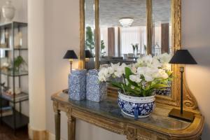 uma mesa com um espelho e um vaso de flores sobre ela em Hotel Imperial Palace em Lido di Jesolo